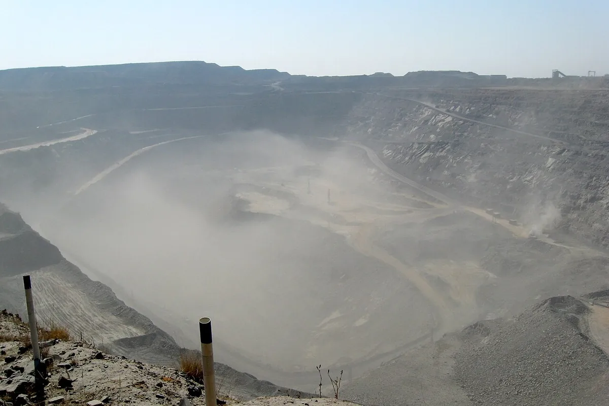 Wide terraced open pit at Jwaneng half hidden by dust